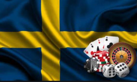 Spelkort, spelmarker, tärningar och ett roulettbord med en svensk flagga i bakgrunden.